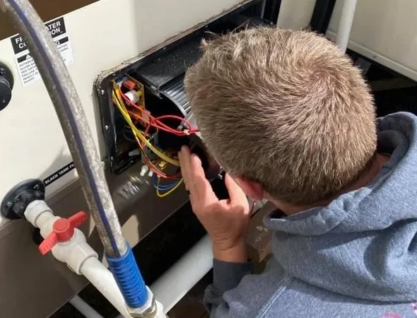 A man is engaged in fixing a water heater indoors, highlighting professional skills in A/C and furnace maintenance.