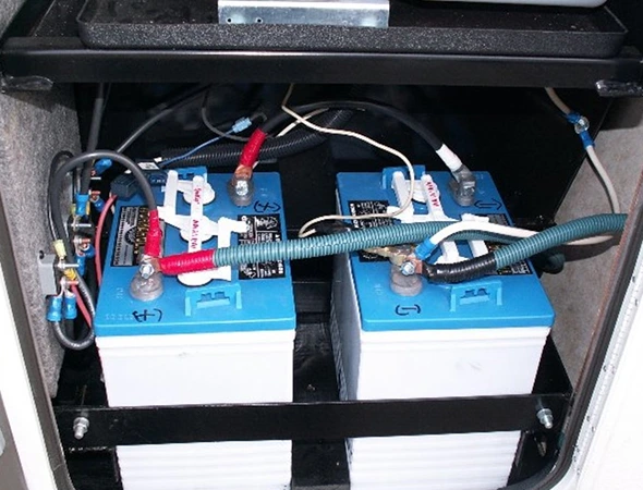 A battery box containing two batteries and wires, illustrating components used in electrical and power systems.