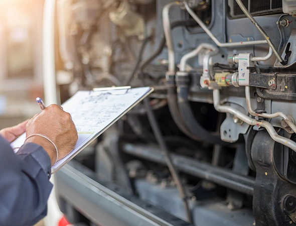 A man is reviewing a truck with a clipboard in hand, underscoring the significance of regular inspection and preventative maintenance.