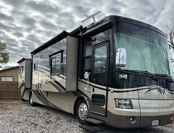 A large motor home is parked in a gravel lot, showcasing effective interior and exterior lighting solutions for enhanced visibility.