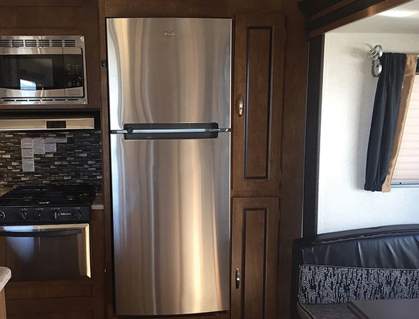 A compact RV kitchen featuring a refrigerator and microwave, showcasing efficient use of space for cooking and food storage.