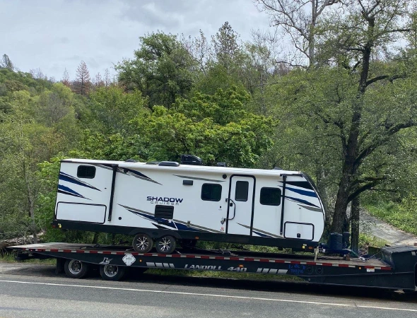 A flatbed truck is seen towing a trailer, illustrating the combination of vehicles for transporting goods or equipment.
